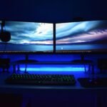 Dual monitors with blue lighting on a gaming desk setup.